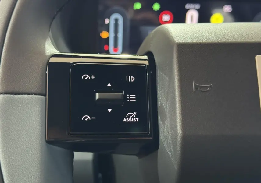 Gros plan sur les commandes multifonctions noires à gauche du volant de la Fiat Grande Panda marron 2025.