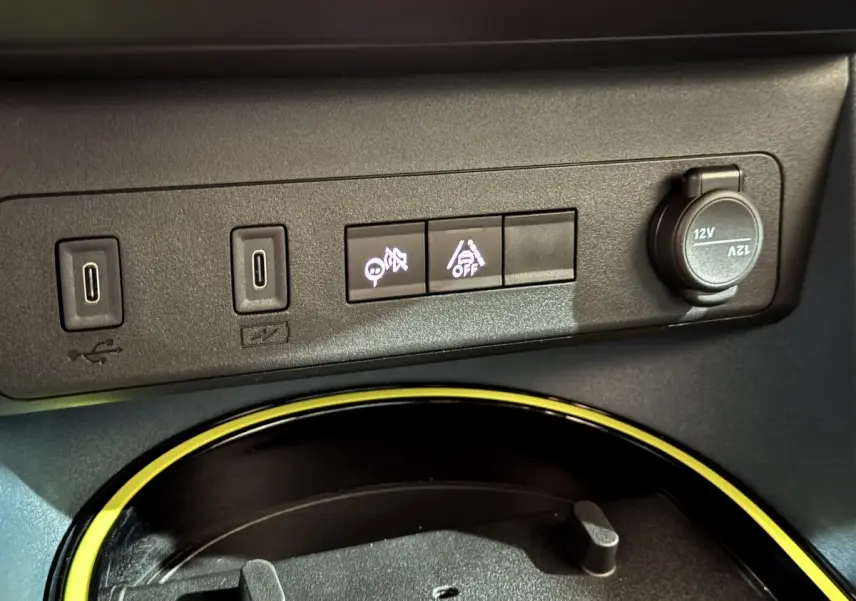 Gros plan sur la console centrale de la Fiat Grande Panda marron, montrant ports USB, boutons d’aide à la conduite et prise 12V.