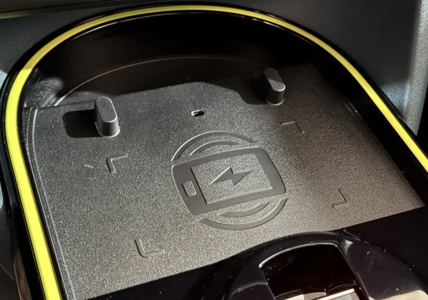 Gros plan sur la zone de recharge par induction noire avec contour jaune dans l’habitacle de la Fiat Grande Panda marron 2025.