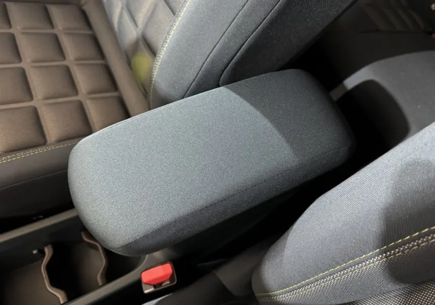 Accoudoir central gris foncé et sièges tissu marron avec surpiqûres jaunes dans une Fiat Grande Panda 2025.