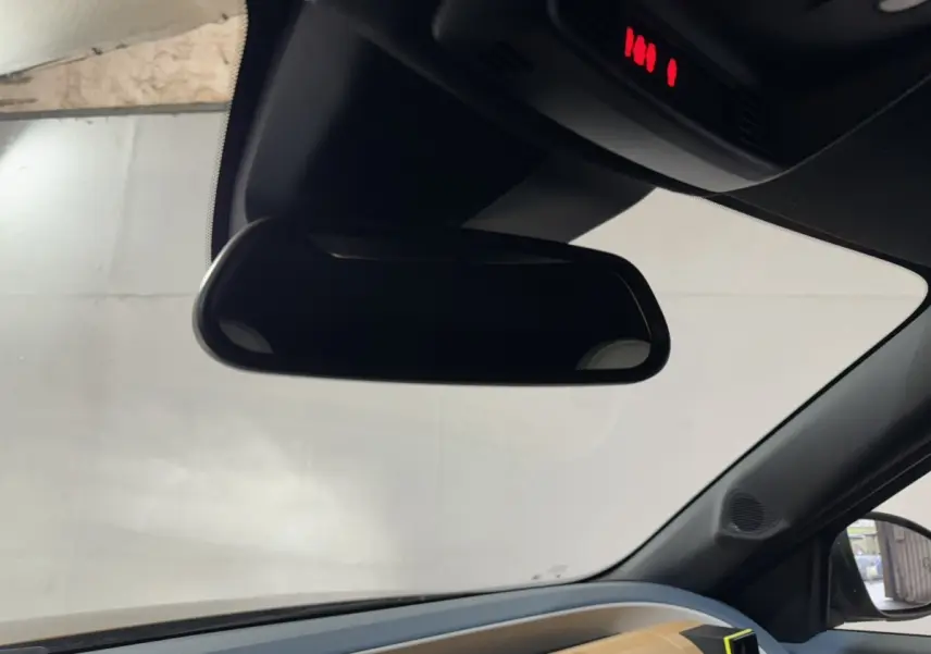 Rétroviseur intérieur vu de l'habitacle d'une Fiat Grande Panda 2025, avec tableau de bord marron visible côté droit.