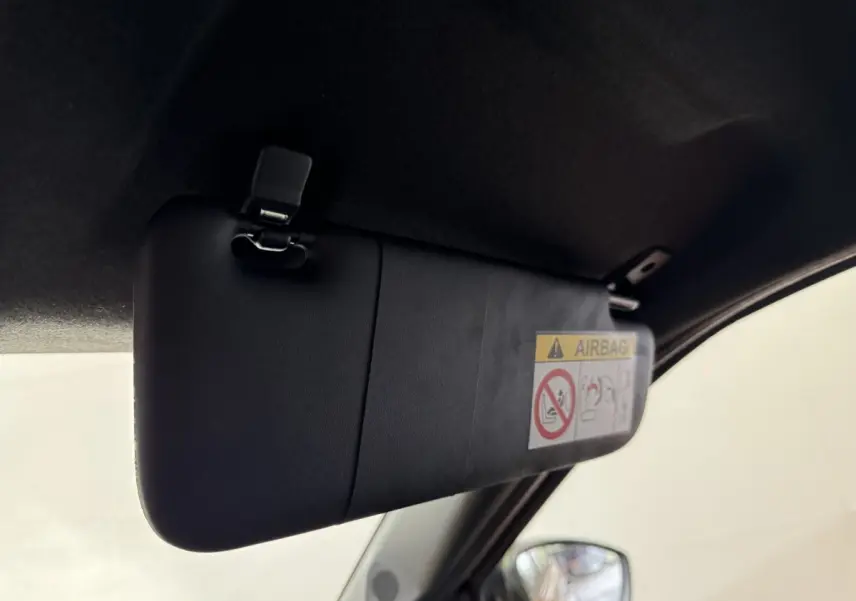 Détail du pare-soleil côté conducteur avec étiquette airbag, rétro électrique visible sur une FIAT Grande Panda marron.