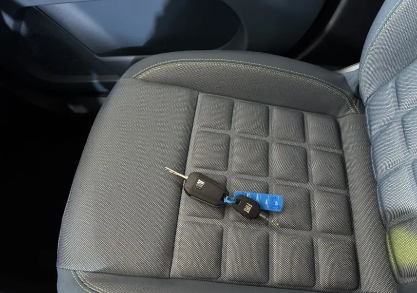Gros plan sur la clé FIAT posée sur le siège avant gris à surpiqûres jaunes de la Grande Panda 2025.