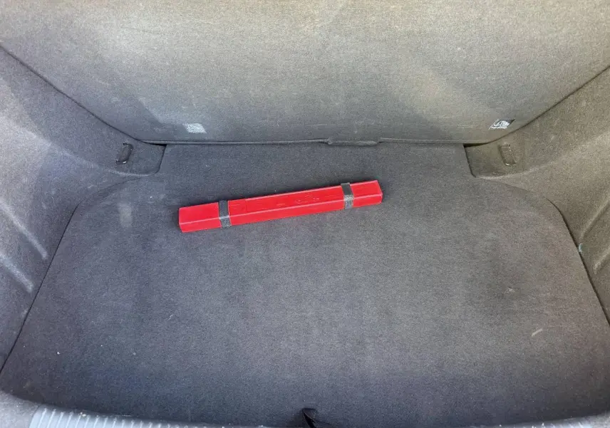 Coffre ouvert de MG3 1.5 Hybrid+ 2024 en Pebble Black, avec tapis noir et triangle de signalisation rouge posé au centre.