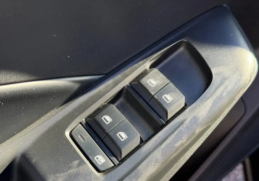 Gros plan sur les commandes des vitres électriques côté conducteur de la MG3 1.5 Hybrid+ Pebble Black 2024.