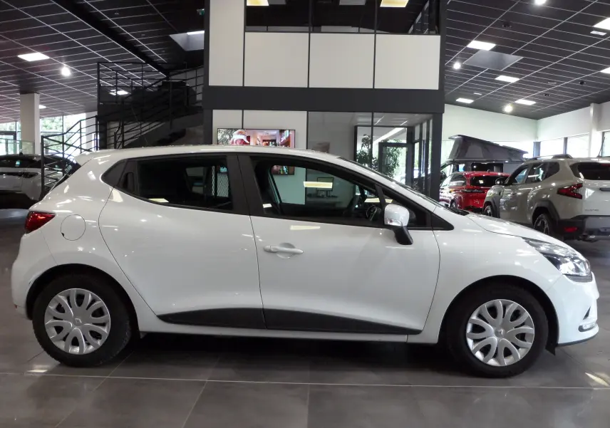 Profil côté gauche d'une Renault Clio IV Société blanche Glacier 2019 en intérieur, avec jantes acier et rétroviseurs blancs.