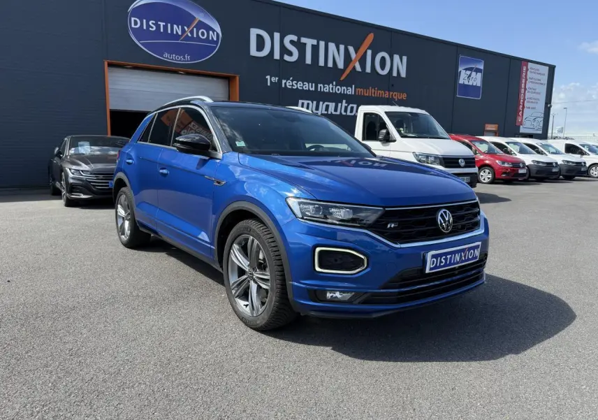 Volkswagen T-Roc bleu Ravenna métallisé en 3/4 avant droit avec jantes alliage noir diamanté sur parking extérieur.