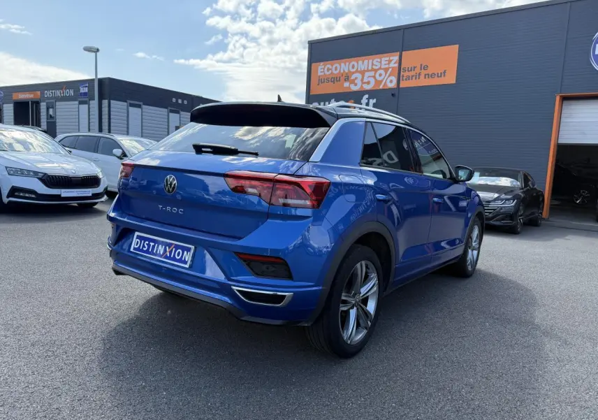 Volkswagen T-Roc bleu Ravenna métallisé vu en 3/4 arrière droit avec jantes alliage et toit noir.