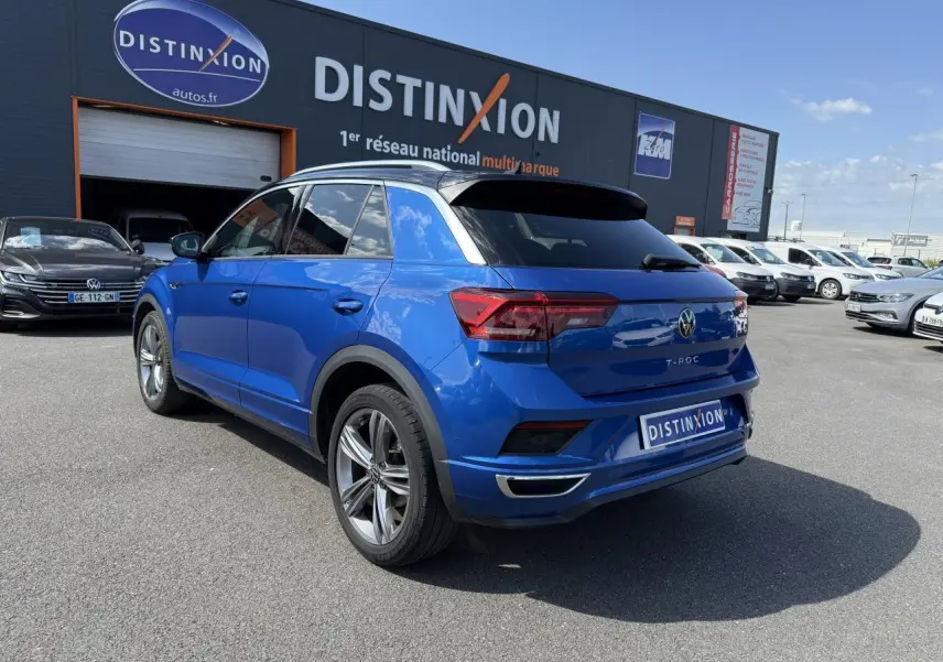 Volkswagen T-Roc bleu Ravenna métallisé vu de l'arrière côté gauche, avec jantes alliage 18 pouces et toit noir.