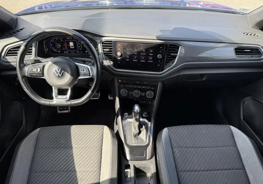 Vue intérieure avant du Volkswagen T-Roc 2022 avec tableau de bord numérique, volant cuir multifonction et console centrale moderne.