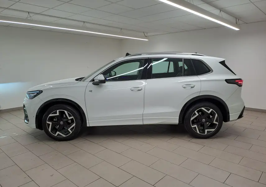 Vue de profil côté gauche du Volkswagen Tiguan blanc pur 2025, finition R-Line avec jantes distinctives noires et argentées.