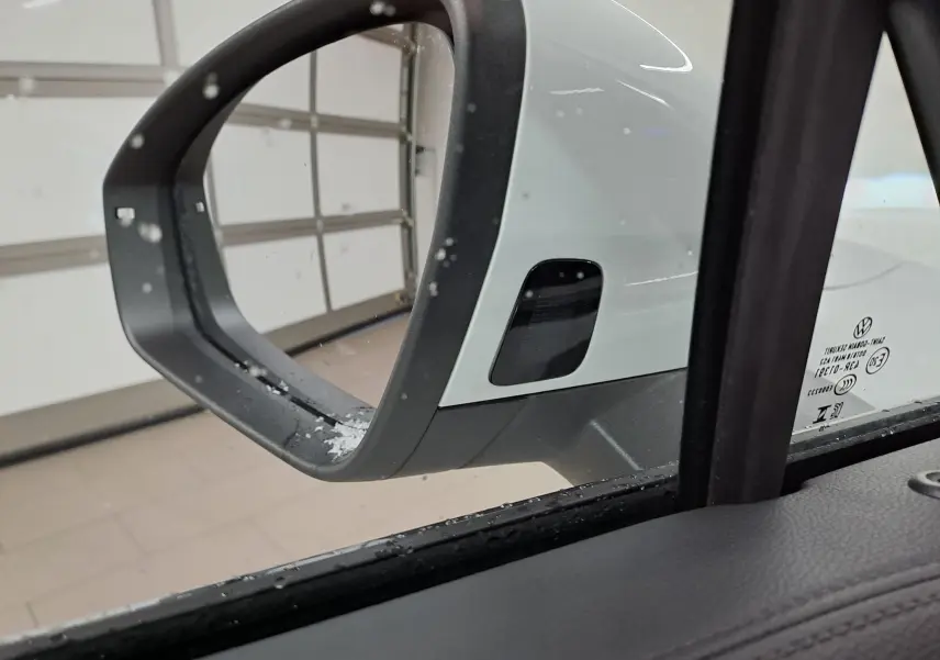 Rétroviseur extérieur côté gauche blanc pur du Volkswagen Tiguan 1.5 eTSI 150ch R-Line Edition 2025, vue depuis l'intérieur.