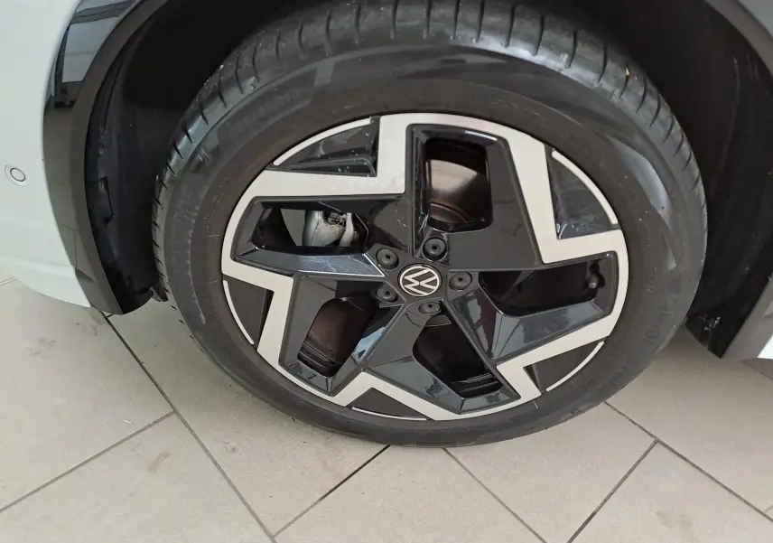 Gros plan sur la roue avant gauche du Volkswagen Tiguan blanc pur, avec jante alliage noire et argentée au design moderne.