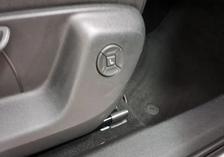 Gros plan sur le bouton de réglage électrique du siège côté conducteur du Volkswagen Tiguan blanc pur 2025.