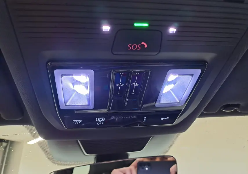 Vue intérieure en plongée sur le plafonnier avec éclairages et bouton SOS du Volkswagen Tiguan blanc pur 2025 R-Line Edition.