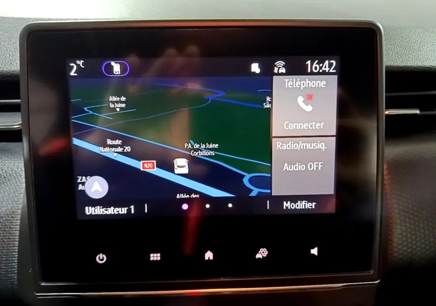 Écran tactile central du tableau de bord de la Renault Clio Business bleu, affichant la navigation et options téléphone.
