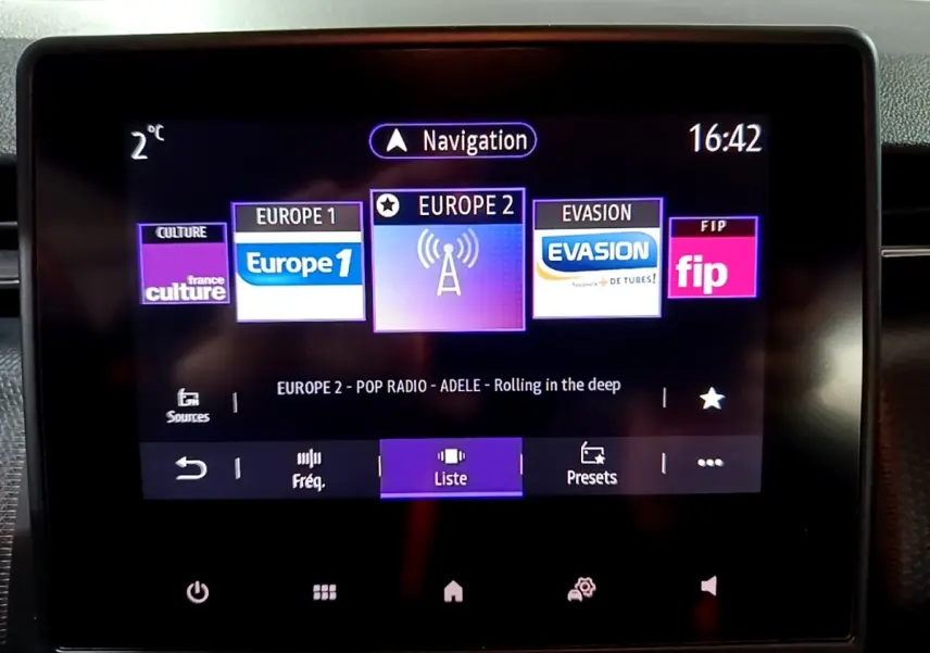 Écran tactile central du tableau de bord de la Renault Clio Business bleu, affichant les stations radio et la navigation.