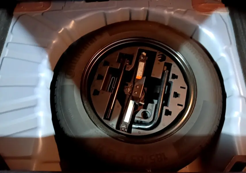 Vue rapprochée de la roue de secours et des outils de bord dans le coffre d’une Renault Clio Business bleu.