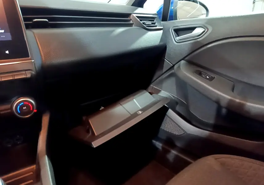 Intérieur de la Renault Clio Business bleu, vue côté passager avec boîte à gants ouverte et tableau de bord noir.