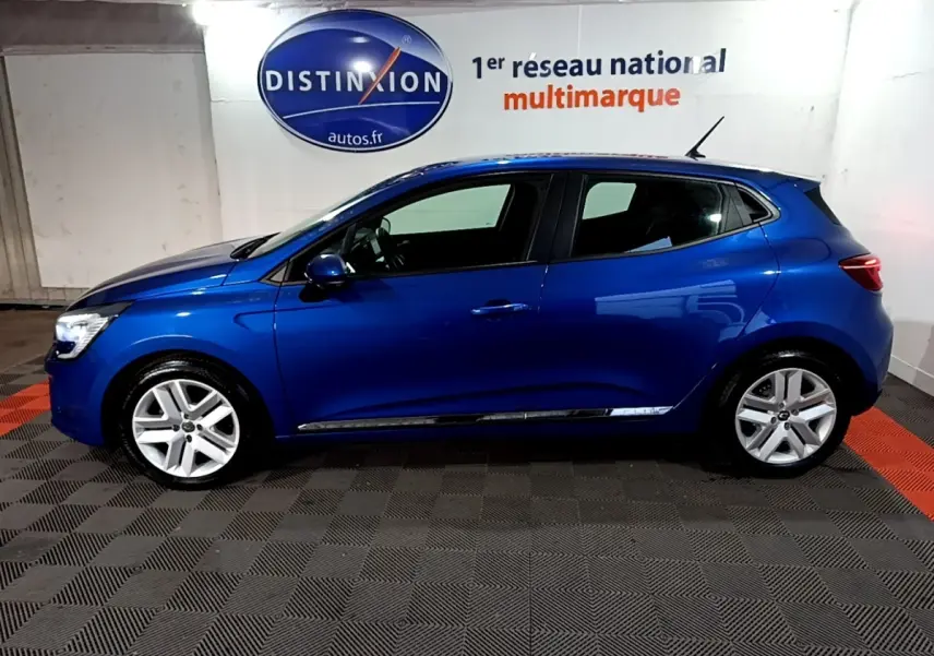 Profil droit d'une Renault Clio Business bleu vif, avec jantes alliage et rétroviseurs assortis, en intérieur showroom.