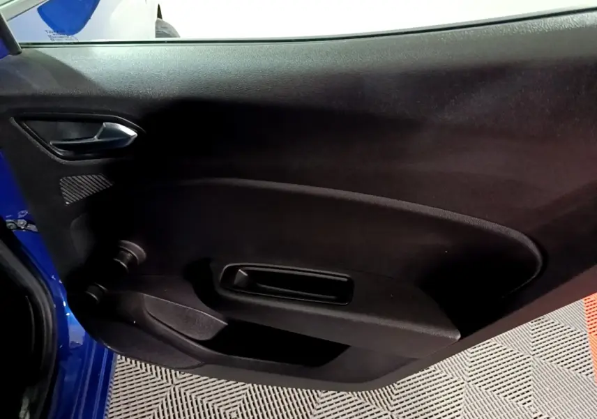 Vue intérieure de la porte côté gauche d'une Renault Clio Business bleu 2022, avec poignée et commande de vitre manuelle.