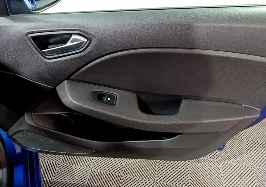 Vue rapprochée de la porte avant gauche noire avec poignée argentée et bouton de commande de vitre d’une Renault Clio bleu.
