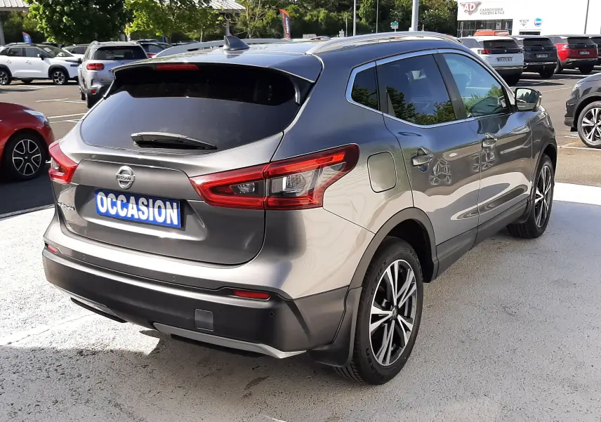Vue 3/4 arrière droite d'un Nissan Qashqai 2018 marron métal avec jantes alliage et vitres teintées sur parking.