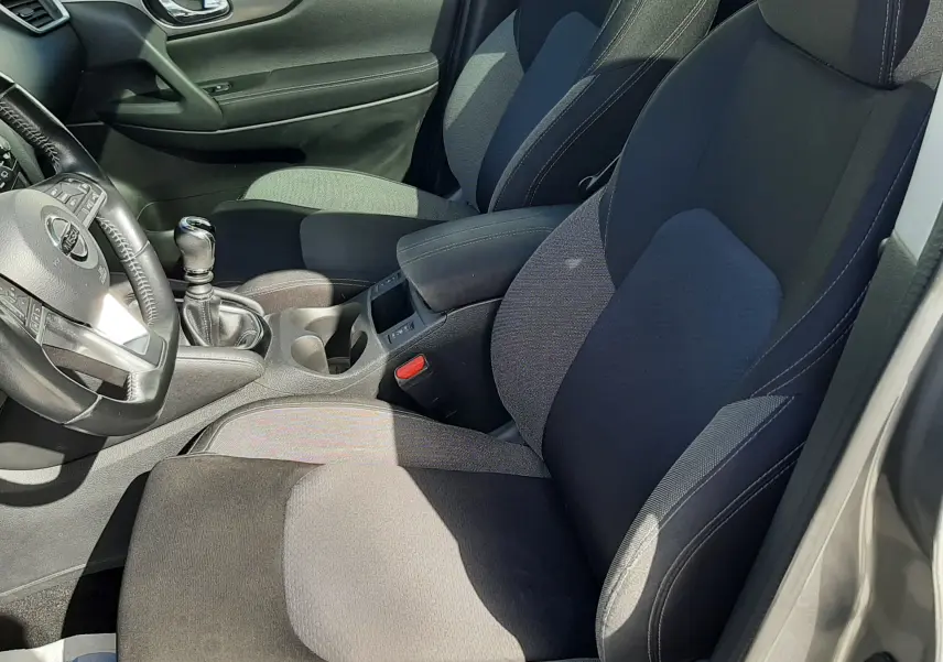 Vue intérieure côté gauche du Nissan Qashqai 2018, sièges tissu gris noir avec console centrale et levier de vitesses manuel.