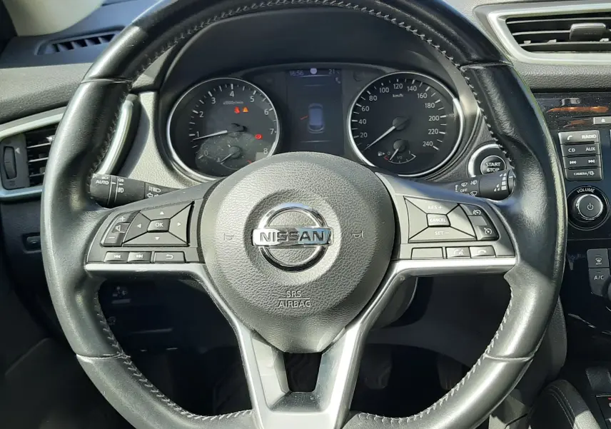 Vue intérieure centrée sur le volant en cuir noir du Nissan Qashqai 2018, avec tableau de bord et commandes visibles.