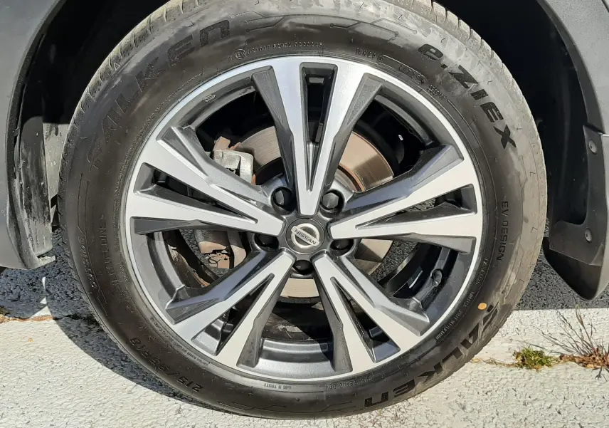 Gros plan sur la roue avant droite du Nissan Qashqai marron métal, jante alliage bicolore au design moderne.