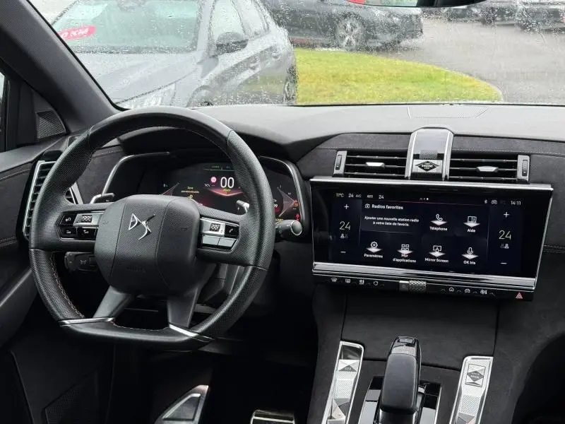 Vue intérieure du tableau de bord et volant du DS7 E-TENSE gris 2024, avec écran tactile central et commandes modernes.