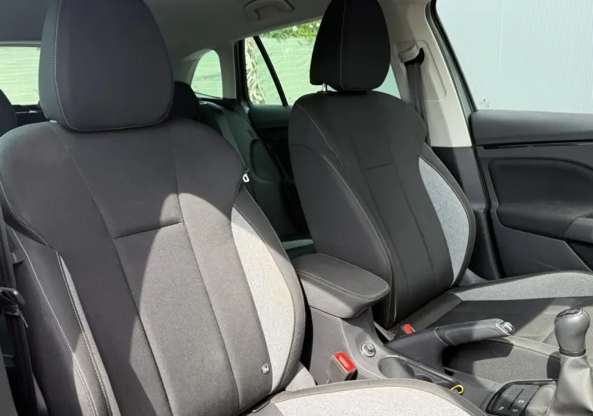Vue intérieure des sièges avant noirs et gris d'une Skoda Scala TSI 116 Sélection avec accoudoir central et levier de vitesses manuel.