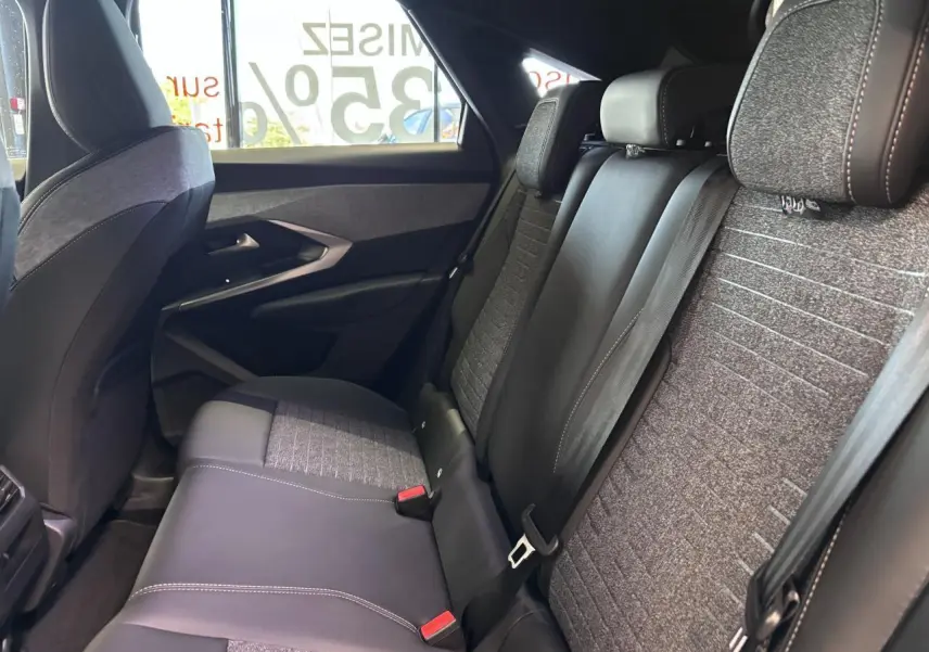 Vue intérieure côté droit des sièges arrière gris tissu et cuir du Peugeot 3008 hybride blanc 2026 avec ceintures de sécurité.