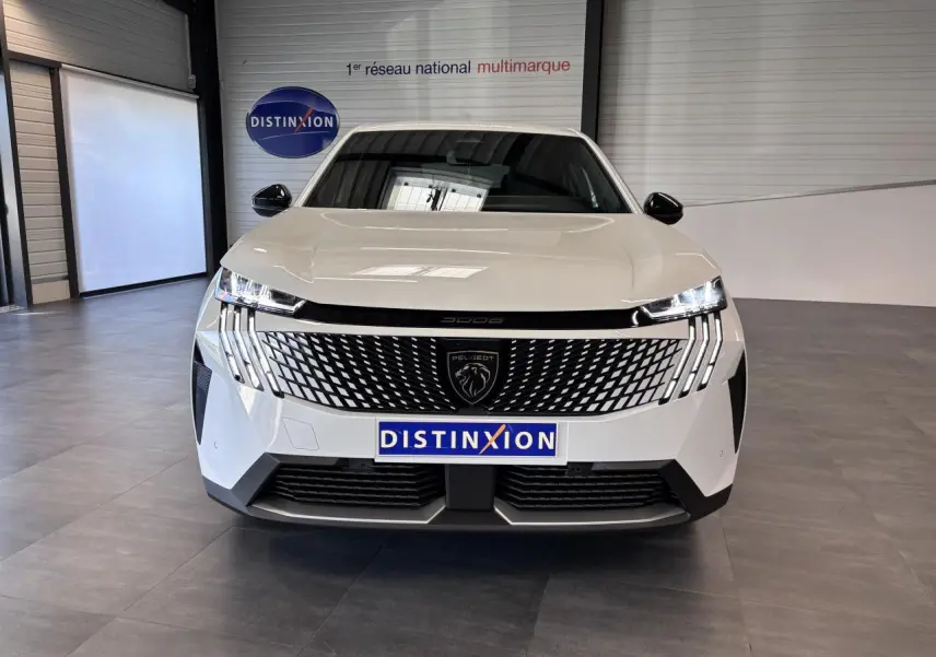 Vue avant d’un Peugeot 3008 blanc avec calandre noire laquée et feux LED à 3 griffes, en intérieur showroom.
