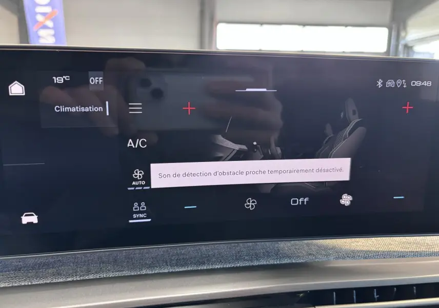 Écran tactile central du Peugeot 3008 blanc, affichant le menu climatisation avec message de détection d'obstacle désactivée.