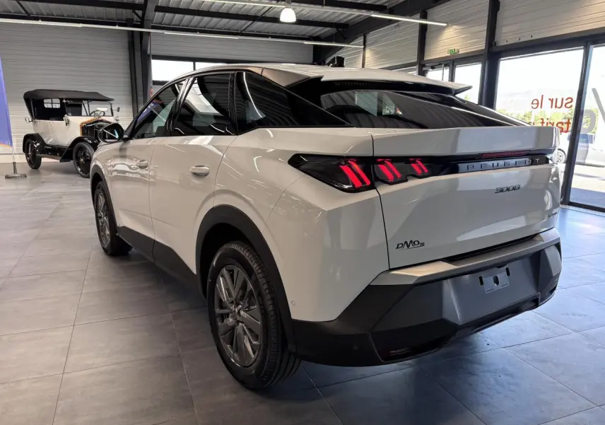 Vue 3/4 arrière droite d'un Peugeot 3008 blanc avec feux arrière LED à 3 griffes et bandeau noir laqué.