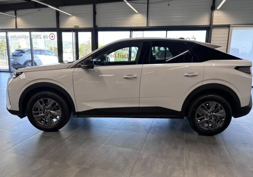 Profil côté gauche d'un Peugeot 3008 blanc avec toit noir et jantes alliage 18 pouces dans un showroom.