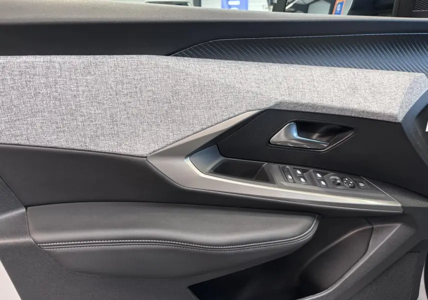 Détail de la porte avant gauche du Peugeot 3008 blanc, avec garniture tissu gris et commandes électriques.