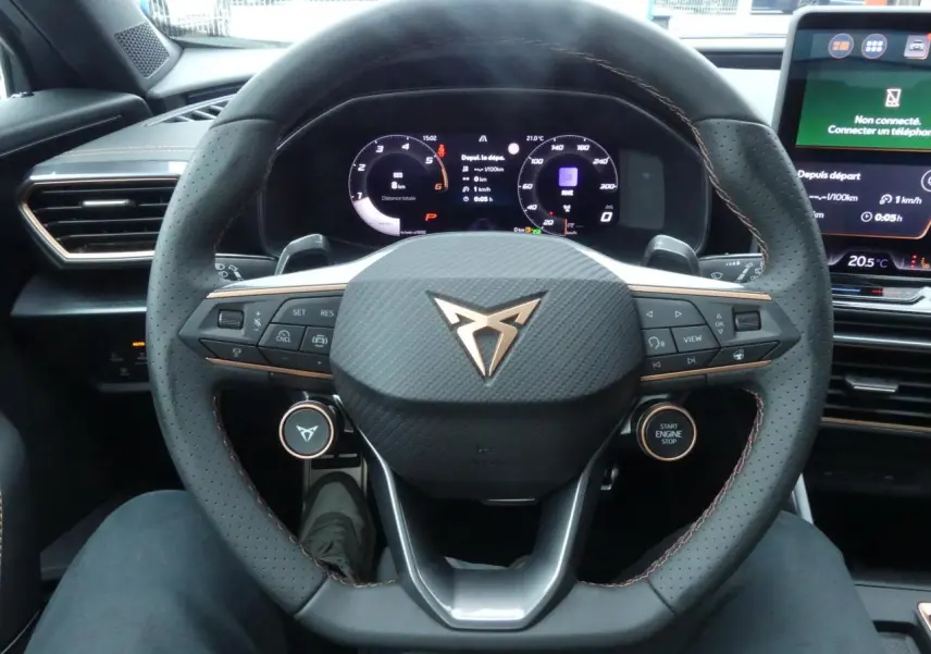 Vue rapprochée du volant perforé noir avec logo CUPRA cuivré et tableau de bord digital du CUPRA Formentor gris Graphène 2025.