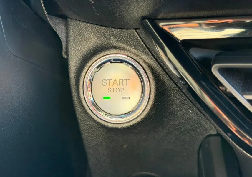 Détail du bouton Start/Stop rond avec éclairage vert sur tableau de bord noir d'une MG3 1.5 Hybrid+ 2024.