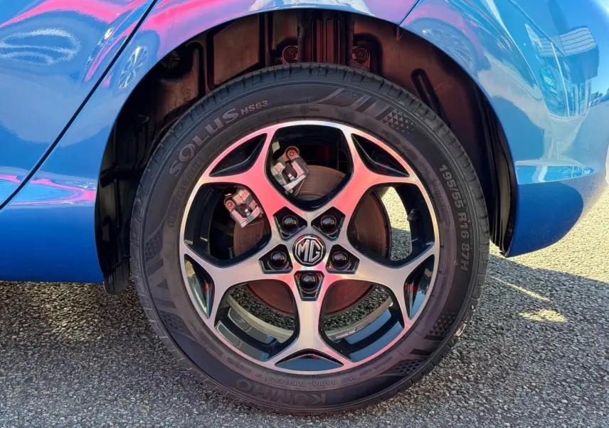 Gros plan sur la roue avant droite d'une MG3 1.5 Hybrid+ 2024 en Como Blue métallisé, avec jante alliage à cinq branches.