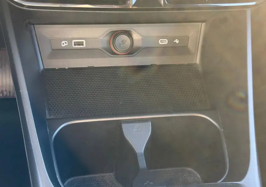 Gros plan sur la console centrale noire du MG3 1.5 Hybrid+ 2024 avec prise 12V, USB et rangement intégré.