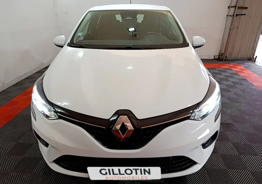 Vue avant d'une Renault Clio Business TCe 100 blanche avec phares LED allumés dans un garage.