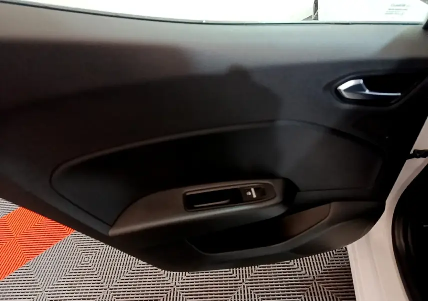 Vue rapprochée de la porte intérieure côté droit de la Renault Clio Business TCe 100 blanche, avec commande de vitre électrique.