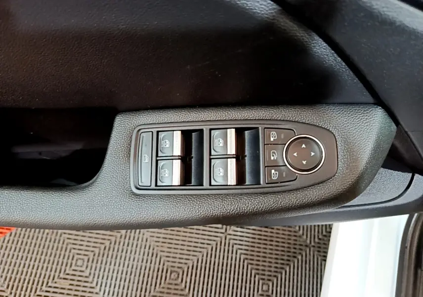 Vue rapprochée des commandes électriques des vitres sur la porte côté gauche d’une Renault Clio Business blanche.