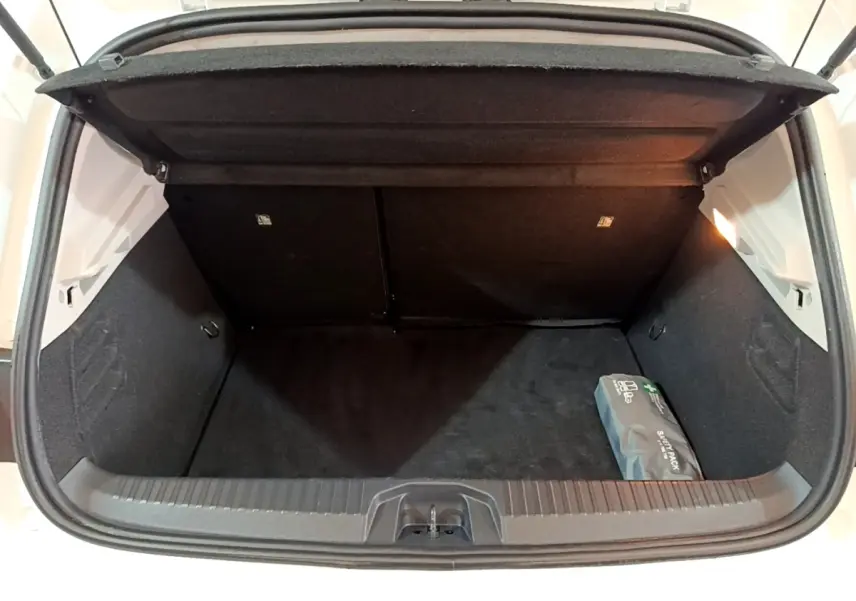 Vue plongeante sur le coffre ouvert blanc d'une Renault Clio 2020, avec un kit de secours visible à droite.