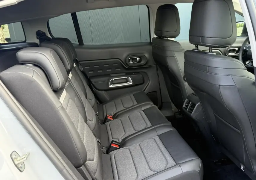 Vue intérieure côté gauche des sièges arrière en tissu et cuir noir du Citroën C5 Aircross blanc Okenite, avec appuie-têtes réglables.