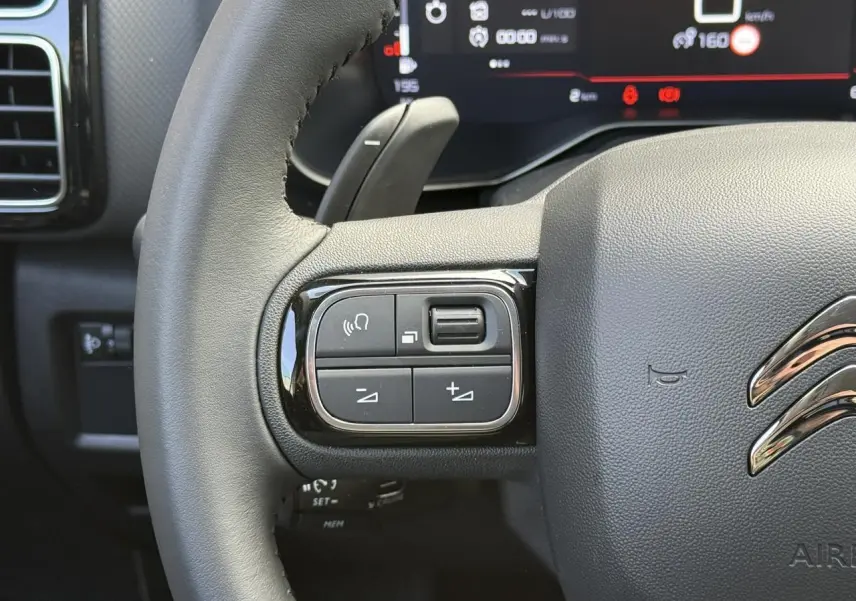 Gros plan sur le volant cuir noir du Citroën C5 Aircross 2026, avec commandes intégrées côté gauche et combiné numérique en arrière-plan.