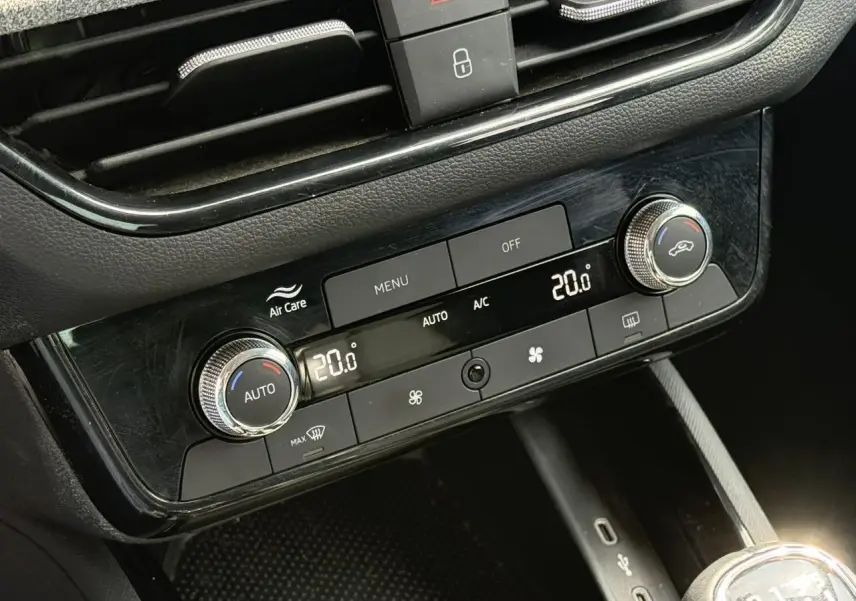 Gros plan sur la console centrale de la Skoda Scala TSI 116 Sélection 2025, montrant la climatisation automatique bi-zone et les commandes en noir brillant.
