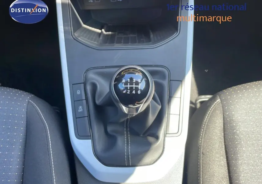 Le levier de vitesse manuel noir du SEAT Arona 2025, vu de dessus entre les sièges gris foncé à motifs.